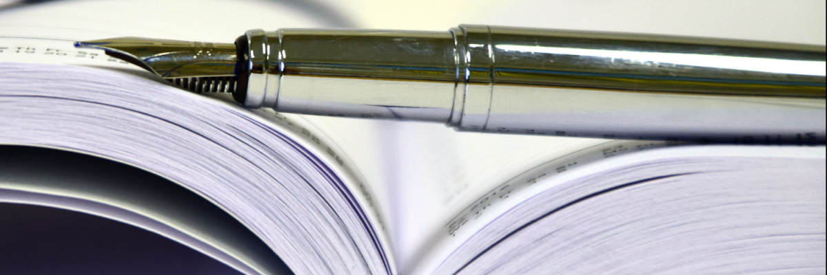 Writing pen over the spine of an open book.